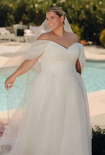 Plus size bride wearing a-line wedding gown with off-the-shoulder straps and sweetheart neckline
