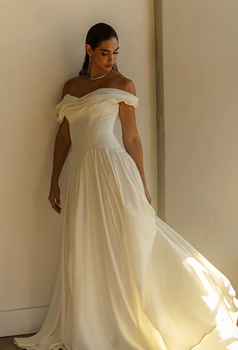 Bride wearing simple boho wedding dress with sweetheart neckline and off-the-shoulder straps