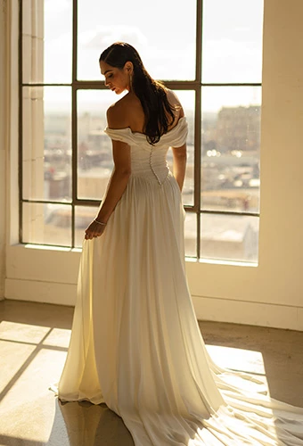 Bride wearing simple boho wedding dress with sweetheart neckline and off-the-shoulder straps