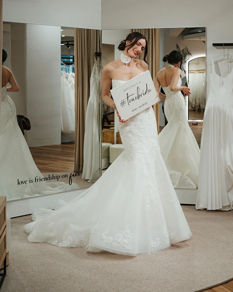 Bride wearing strapless fit-and-flare wedding dress holding a sign