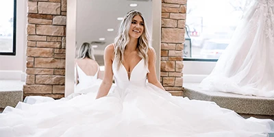 bride sitting in her ballgown wedding dress in front of a mirror