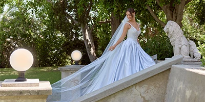 bride walking up stairs in a blue ballgown wedding dress with long veil