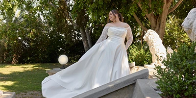 bride wearing a plus size lace long sleeve ballgown with long train