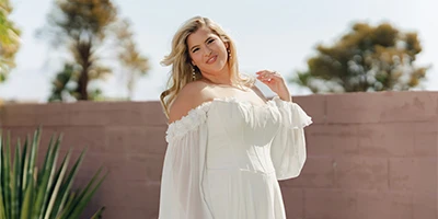 plus size bride posing outside in a flowy off the shoulder wedding dress