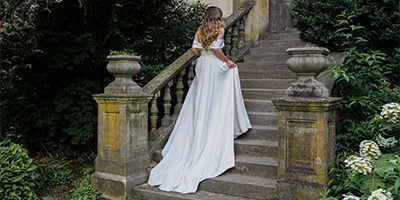 bride hold up her a-line wedding dress to walk up stone steps