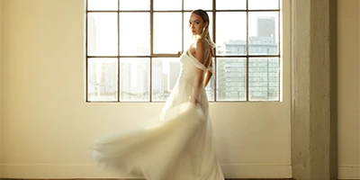 bride spinning in her a-line wedding dress in front of window