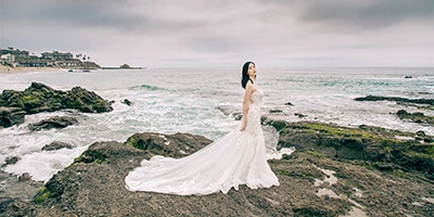bride posing on oceanside rocks in a sparkling mermaid wedding dress