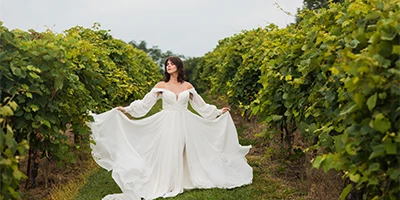 bride holding out wedding dress skirt in a vineyard