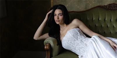 bride laying on a green velvet couch in a sparkling lace wedding dress
