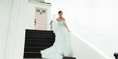 bride standing on stairs wearing a blue and white floral wedding dress