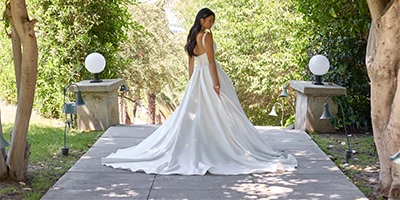 bride standing between pillars looking back over long wedding dress train