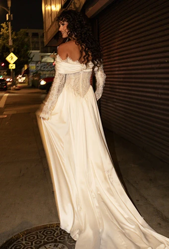 Bride wearing a-line wedding dress with lace corset and lace off-the-shoulder sleeves