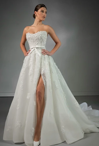 Bride wearing strapless wedding dress with sparkling beads and bow belt detail and high leg slit