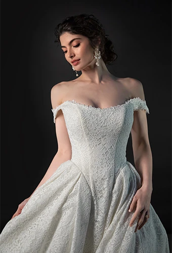 Bride wearing lace ballgown wedding dress with basque waist and off-the-shoulder straps
