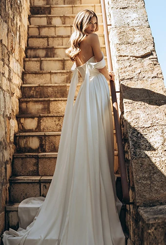 Bride wearing simple wedding dress with off-the-shoulder straps and ribbons