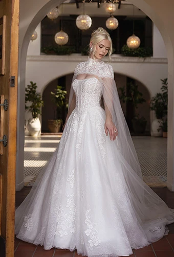 Bride wearing strapless lace ballgown wedding dress with high-neck detachable cape and floral sequin details