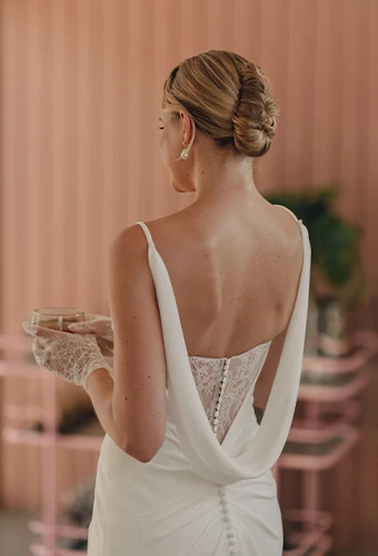 Bride wearing simple crepe wedding dress with lace back detail and detachable cowl