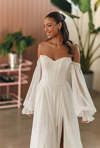 Bride wearing chiffon wedding dress with off-the-shoulder sleeves and high leg slit