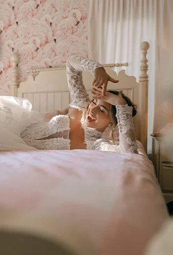 Bride wearing lace ballgown wedding dress with long sleeves lounging on bed