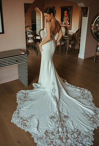 Bride wearing fit-and-flare wedding dress with lace train and fabric-covered buttons