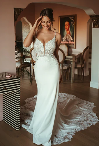 Bride wearing fit-and-flare wedding dress with sweetheart neckline, lace bodice, and thin spaghetti straps
