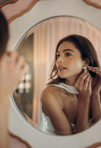 Bride putting on earrings in mirror