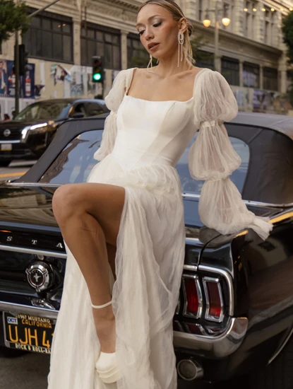 bride wearing boho wedding dress by all who wander while posing on car