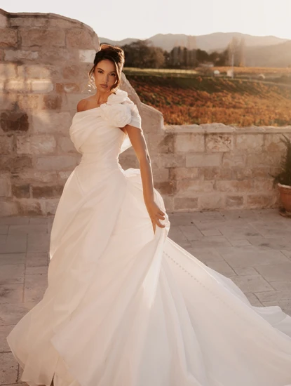 bride wearing one shoulder ballgown wedding dress in a stone courtyard