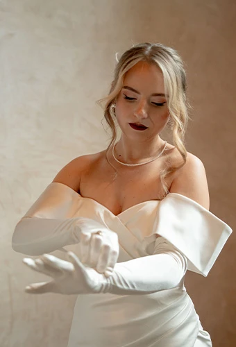 Bride wearing LE1202, a modern sheath off-the-shoulder wedding dress with elegant gloves
