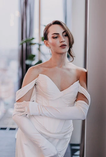 Bride wearing ML1806, a strapless satin column bridal gown with sweetheart neckline, paired with elegant gloves