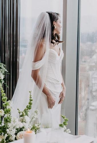 Bride wearing ML1806, a strapless satin column bridal gown with sweetheart neckline, paired with a veil