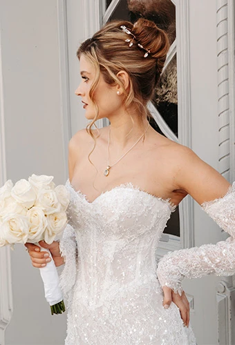 Bride wearing Martina Liana style 1860, a strapless lace column wedding dress with long sleeves, featuring a hair clip