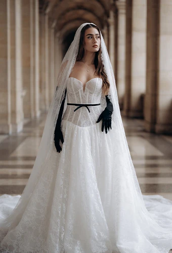 Bride wearing ML1907, a romantic A-line wedding dress with a sweetheart neckline and detachable bow belt, featuring a stunning cathedral veil