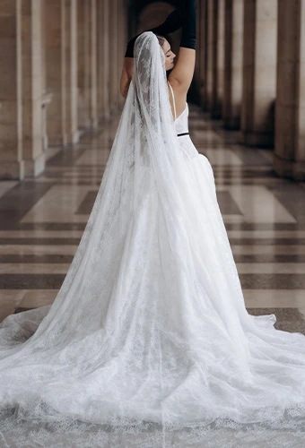 Bride wearing ML1907, an A-line wedding gown with a detachable bow and sweetheart neckline, featuring a cathedral veil