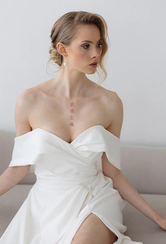 Bride wearing Stella York style 7644, an off-the-shoulder a-line wedding dress, featuring delicate earrings