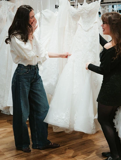 True society bridal stylist helping a bride shop a rack of wedding dresses
