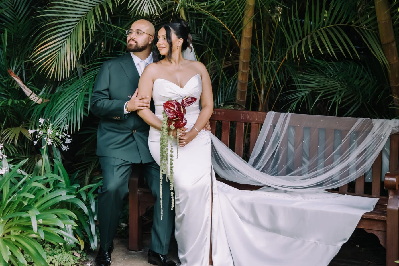 True Bride Kayla and Reece sitting on a bench together surrounded by palm trees