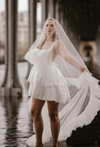 Bride wearing AWW london, a satin short a-line wedding gown with an underskirt, paired with a blusher veil