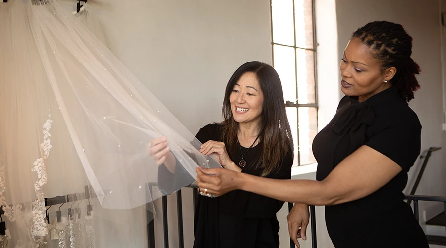 Bridal stylist helping a bride choose a veil