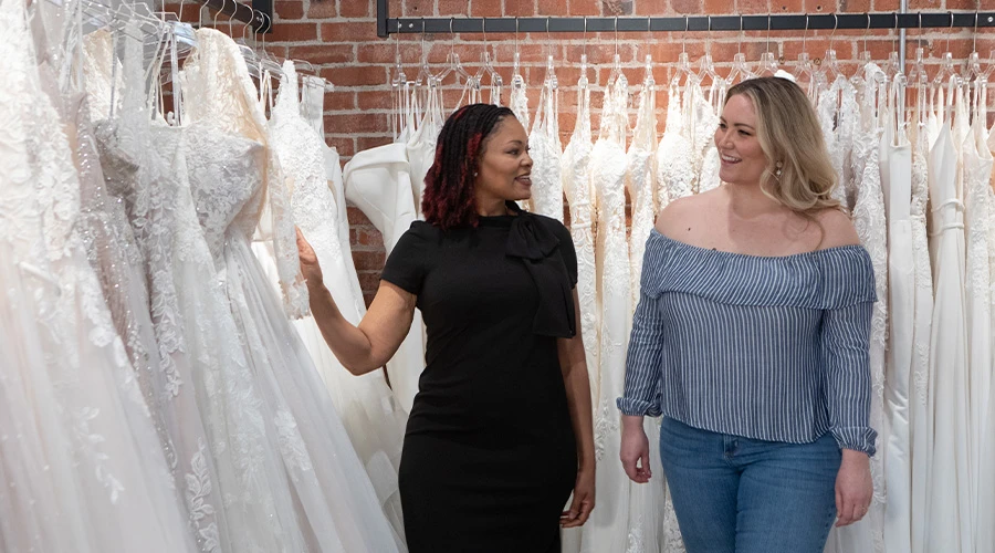 Bridal stylist helping a bride choose a dress to try on at True Society