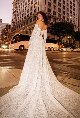 Bride wearing All Who Wander hadley, a lace corset a-line wedding dress with off the shoulder long sleeves