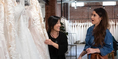 Bridal stylist showing lace wedding dress to bride-to-be at True Society boutique appointment