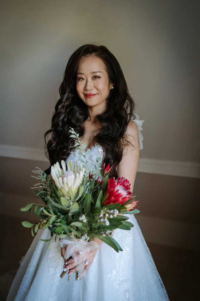 true bride Jess posing in her wedding gown with a bouquet of flowers