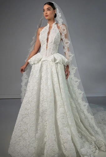 Bride wearing lace halter wedding dress with high neckline peplum waist and veil