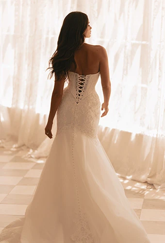 Bride wearing strapless fit and flare wedding gown with lace up back