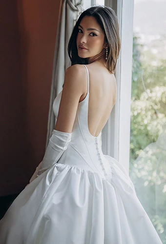 Bride wearing simple ballgown wedding dress with thin spaghetti straps and scoop back
