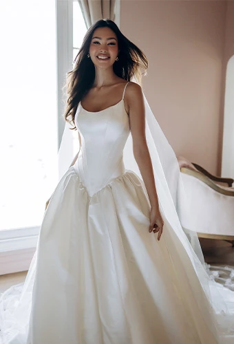 Bride wearing simple ballgown wedding dress with basque drop waist and thin spaghetti straps