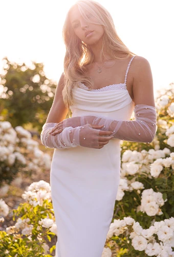 Bride wearing simple wedding gown with pear detailing and long sheet gloves