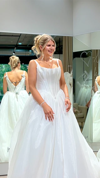 bride standing in front of mirror in simple a-line wedding dress
