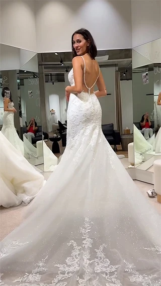 bride standing in a backless mermaid wedding dress in front of boutique mirror